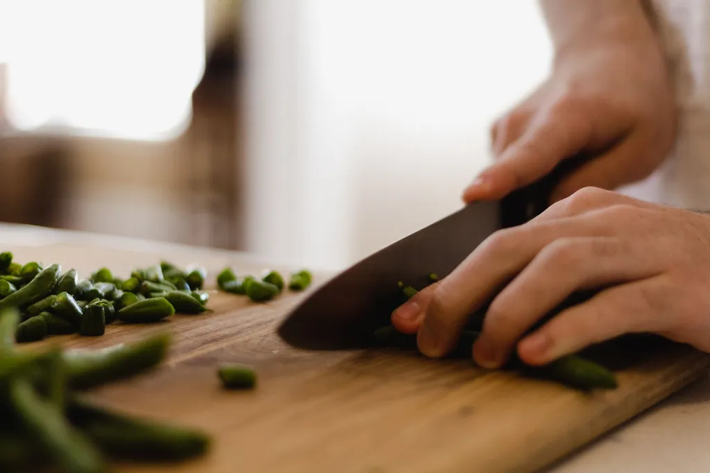 A variety of prepared green beans for dogs displayed on a white surface showing raw, steamed, and bite-sized cut green beans with a happy Labrador Retriever in the background